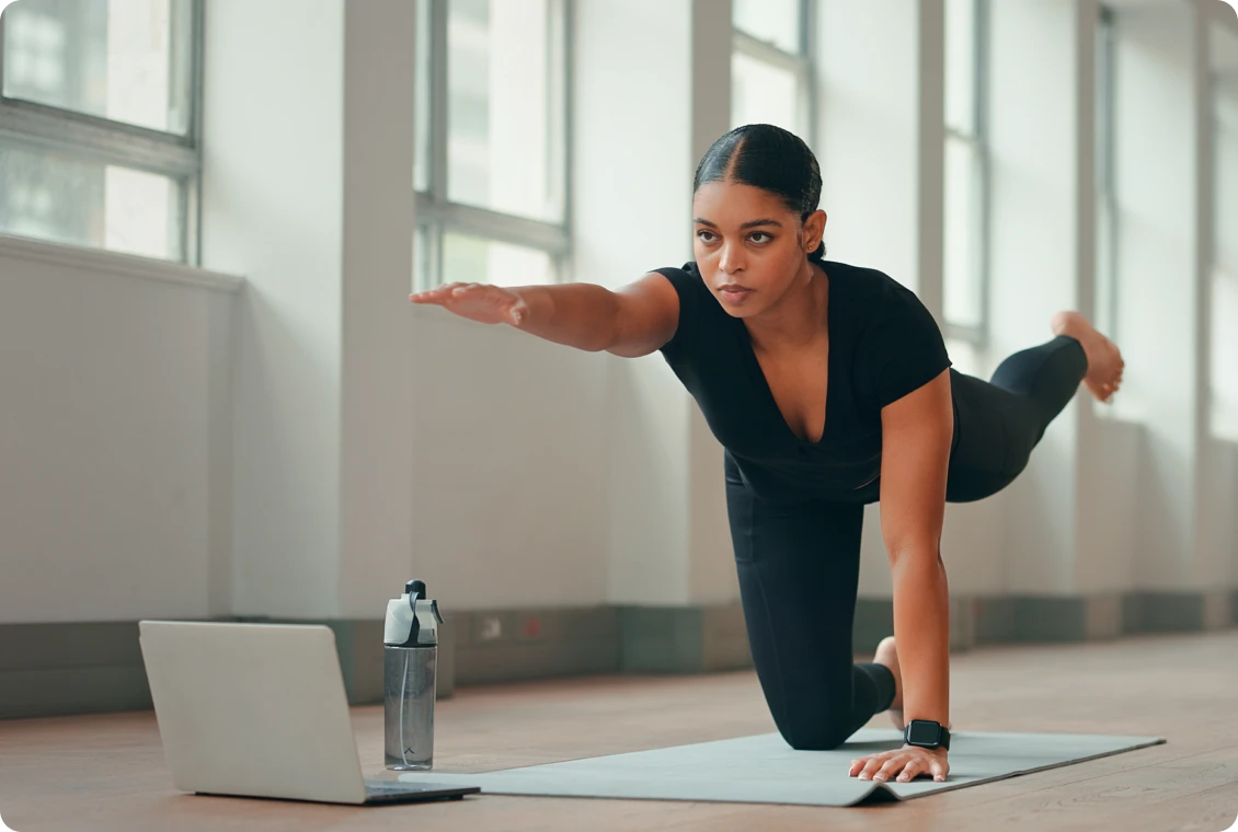 Woman practicing yoga with laptop guidance