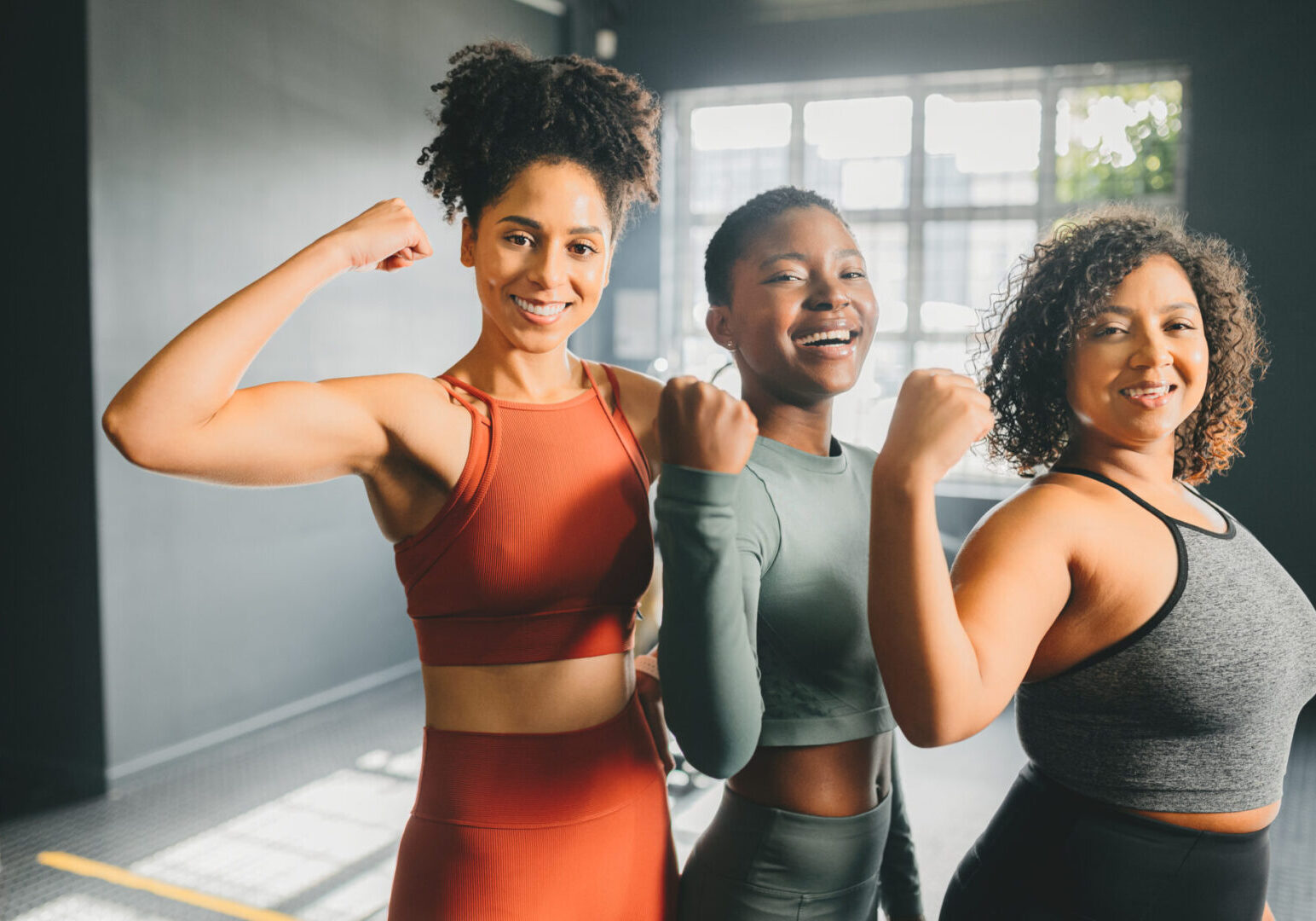 Fitness, training and working with strong women flexing their muscle or bicep in a gym or studio. Motivation, sport and workout with a female athlete and friends in a health center for wellness