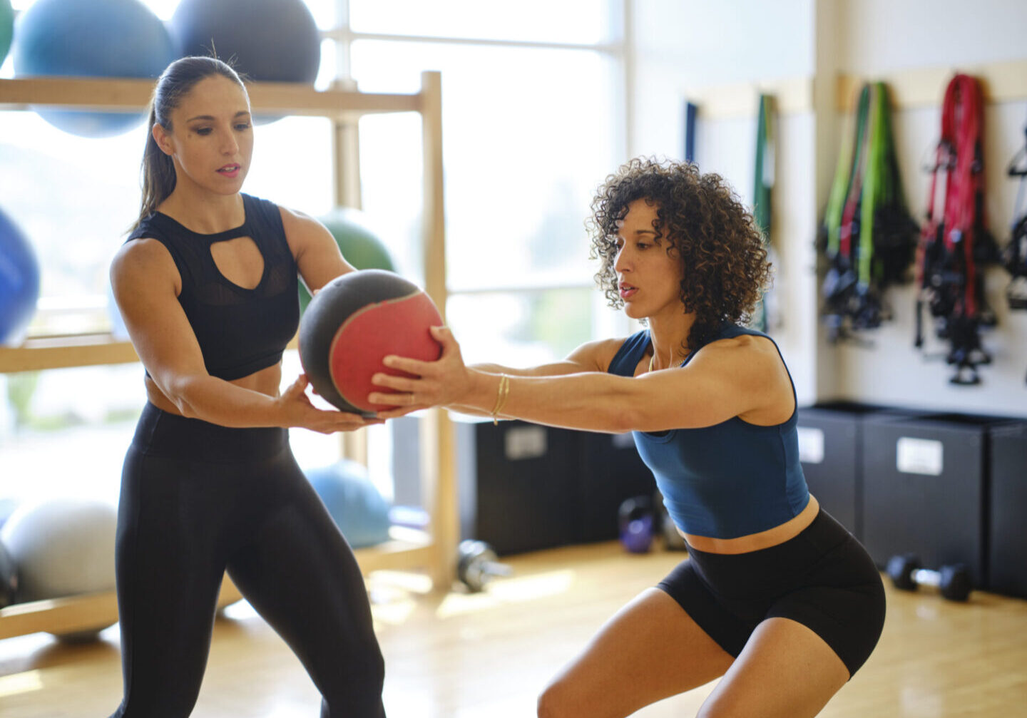 An athletic woman working with a fitness instructor in a gym.
