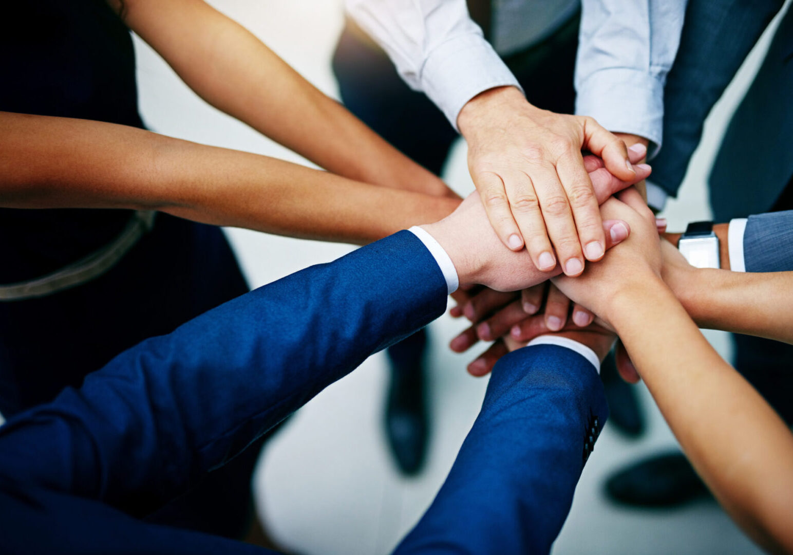 Closeup shot of a group of businesspeople joining their hands together in unity